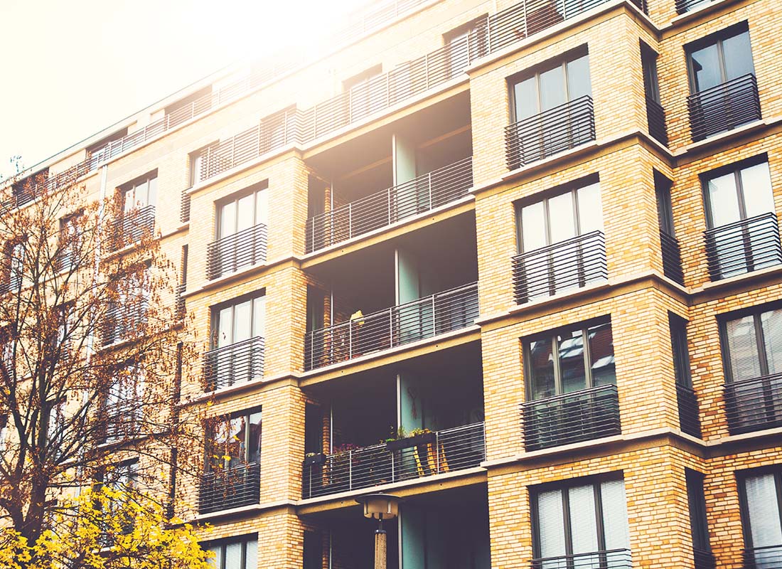 Landlord and Rental Property Insurance - Angled View of a Modern Brick Apartment Building With Warm Sunlight Shining From Above