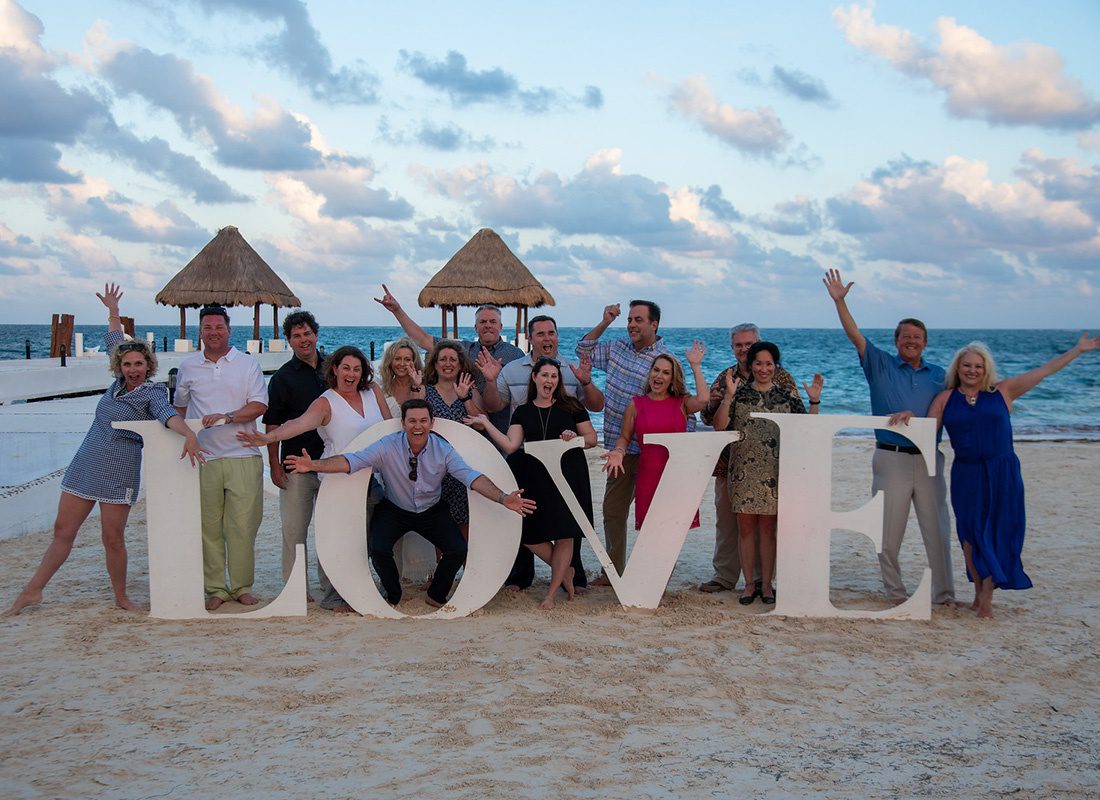 About Our Agency - Portrait of Cheerful Producers on the Southern States Insurance Team Having Fun Posing Next to a Love Sign on a Beach During a Reward Trip to Mexico